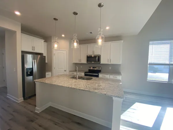 a large kitchen with stainless steel appliances granite countertop a sink a stove and a refrigerator