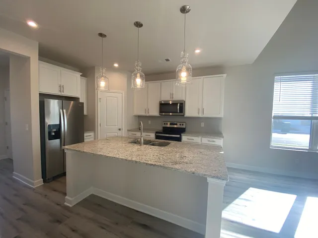 a large kitchen with stainless steel appliances granite countertop a sink a stove and a refrigerator