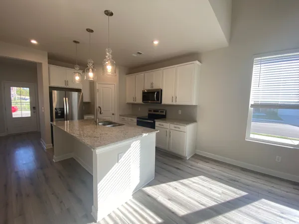 a large kitchen with kitchen island a sink dishwasher a stove a microwave oven and a dining table with wooden floor