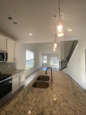 a kitchen with stainless steel appliances kitchen island granite countertop a sink a stove and cabinets