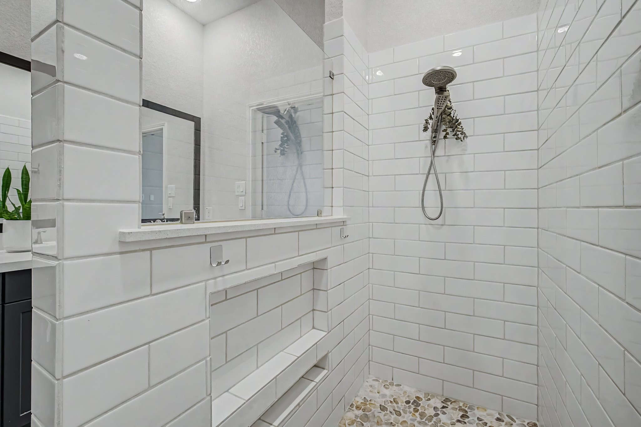21339 Sierra Point Lane Porter, TX 77365 - Photo 19 of 36 Master shower with white subway tiles, a rainfall showerhead, and pebble stone flooring. It features built-in shelves for convenience and a sleek, minimalistic design.