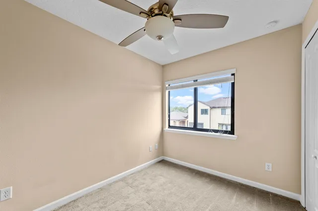 an empty room with a window and a fan