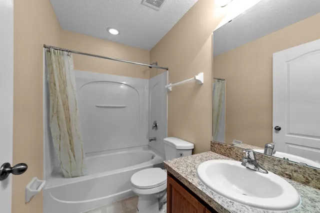 a bathroom with a granite countertop sink mirror and a bathtub