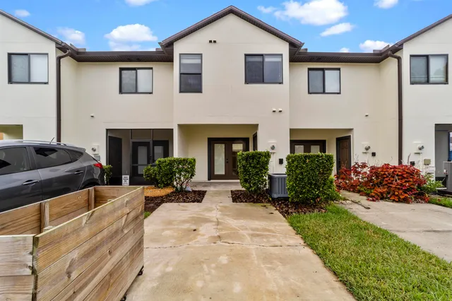a front view of a house with a yard and potted plants