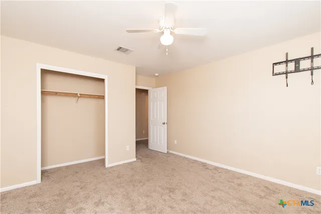 an empty room with chandelier fan and closet