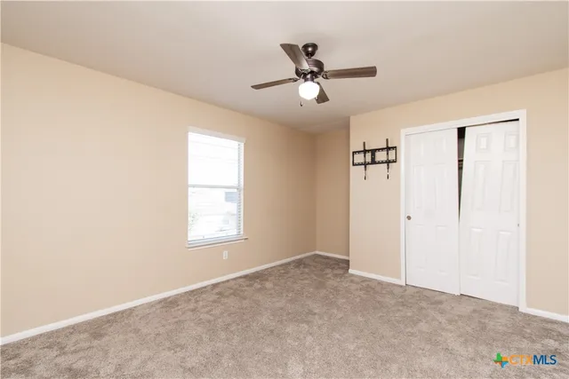 a view of a big room with windows and chandelier fan