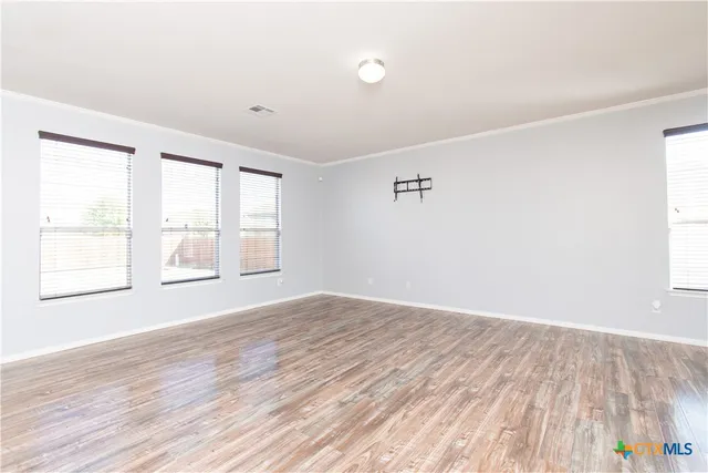 an empty room with wooden floor and windows