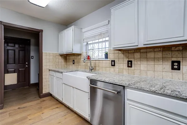 a kitchen with granite countertop a sink stainless steel appliances white cabinets and a window