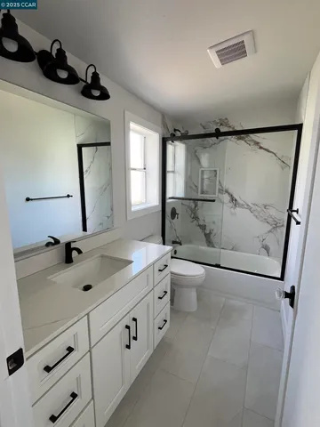 a spacious bathroom with a double vanity sink toilet mirror and bathtub