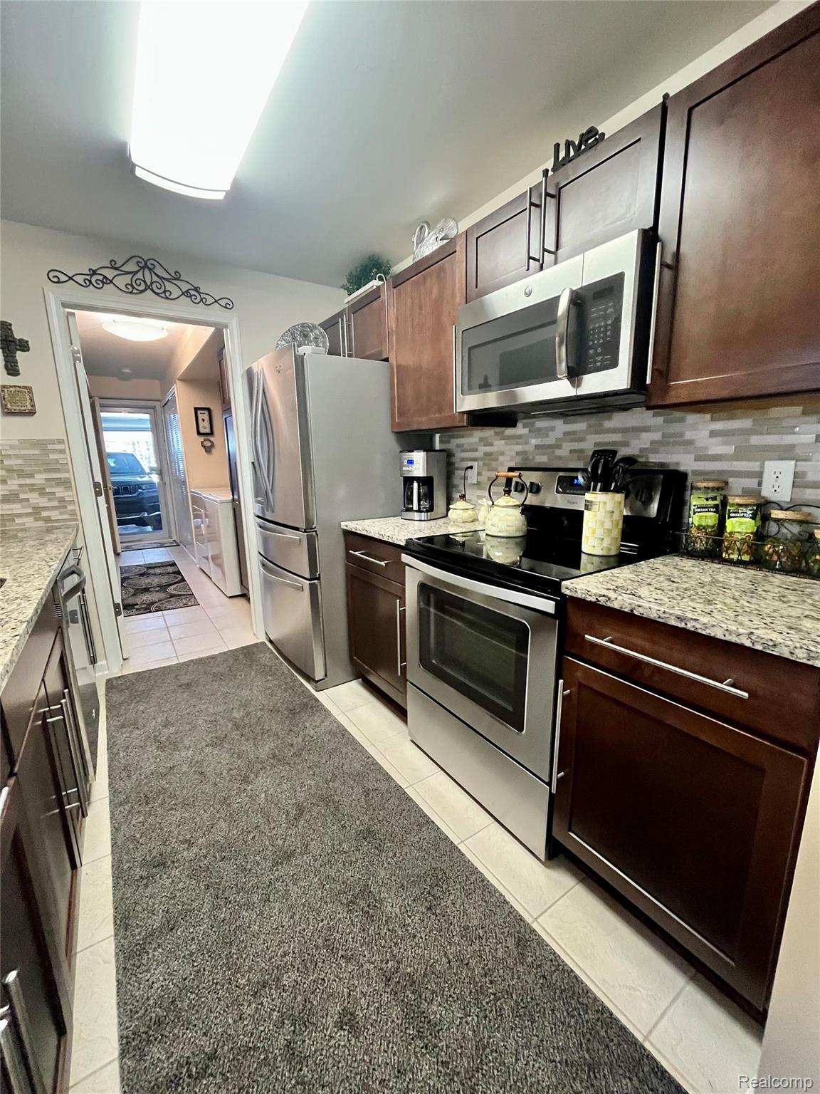 3624 Oakmonte Boulevard, Unit 82 Rochester, MI 48306 - Photo 6 of 37 Kitchen featuring stainless steel appliances, decorative backsplash, light stone counters, and light tile patterned floors