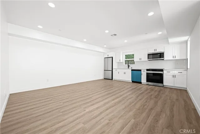 a view of kitchen with stainless steel appliances wooden floor and large window