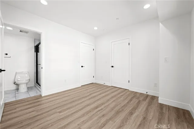 a view of an empty room with wooden floor and a sink