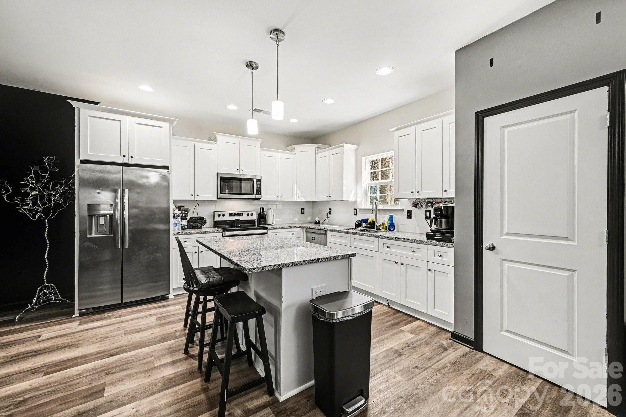 313 Bell Street Mount Holly, NC 28120 - Photo 2 of 19 a kitchen with stainless steel appliances kitchen island granite countertop a refrigerator a stove a sink a dining table and chairs with wooden floor