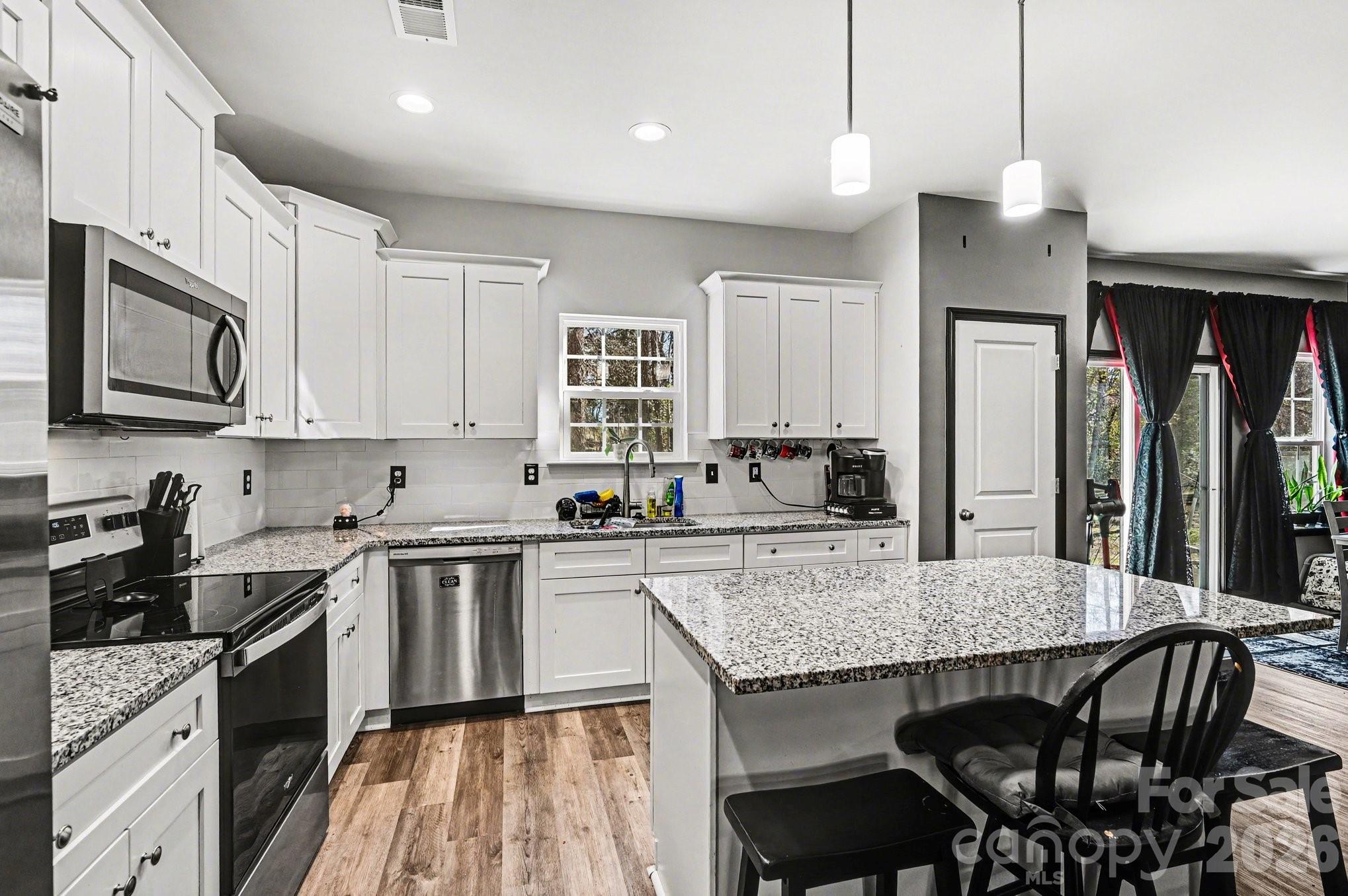313 Bell Street Mount Holly, NC 28120 - Photo 8 of 19 a kitchen with stainless steel appliances granite countertop a stove top oven a sink a counter space and cabinets