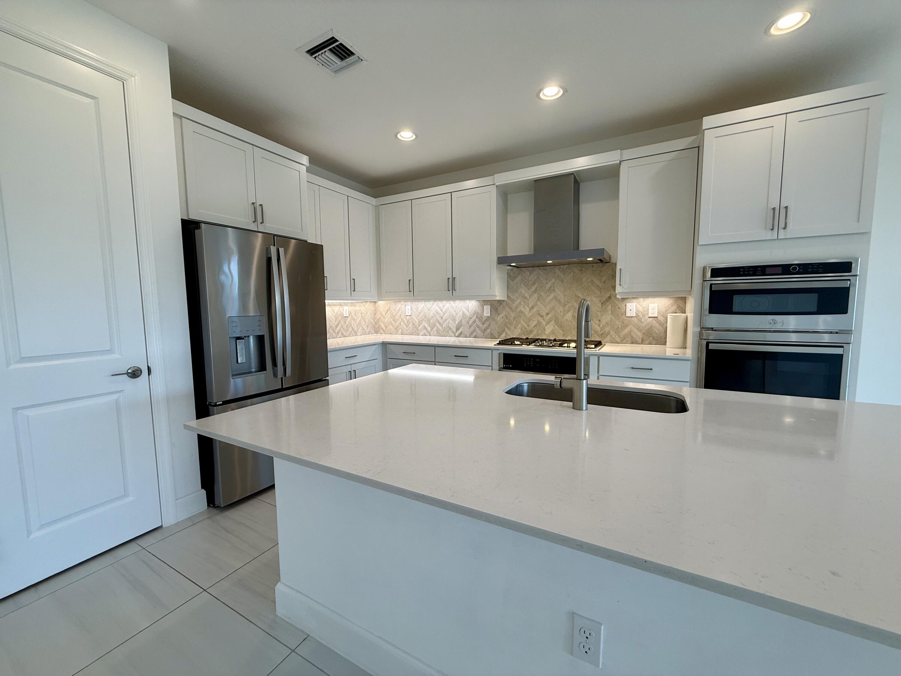 1346 Harvester Crossing Loxahatchee, FL 33470 - Photo 12 of 43 a kitchen with stainless steel appliances a refrigerator sink and stove