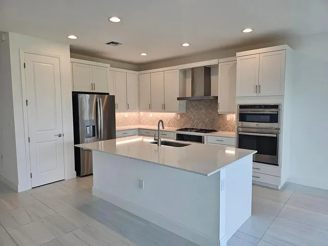 a kitchen with stainless steel appliances a refrigerator sink and white cabinets
