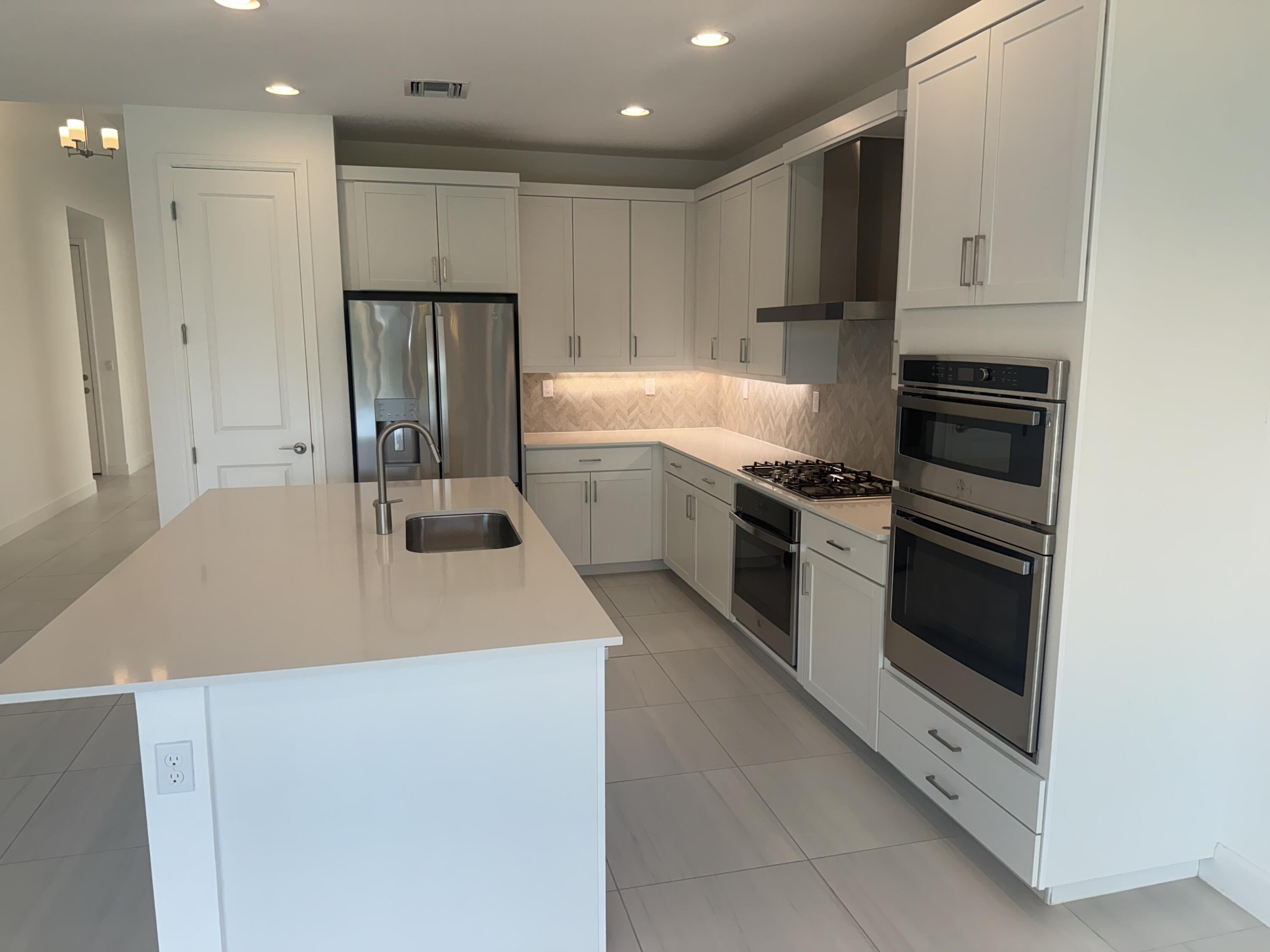 1346 Harvester Crossing Loxahatchee, FL 33470 - Photo 16 of 43 a kitchen with a sink a stove and refrigerator