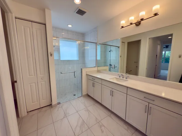 a spacious bathroom with a double vanity sink a mirror and a shower