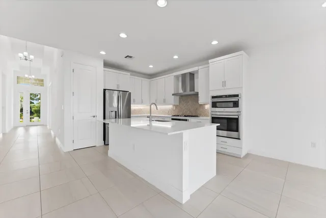 a large white kitchen with stainless steel appliances a refrigerator and a stove top oven