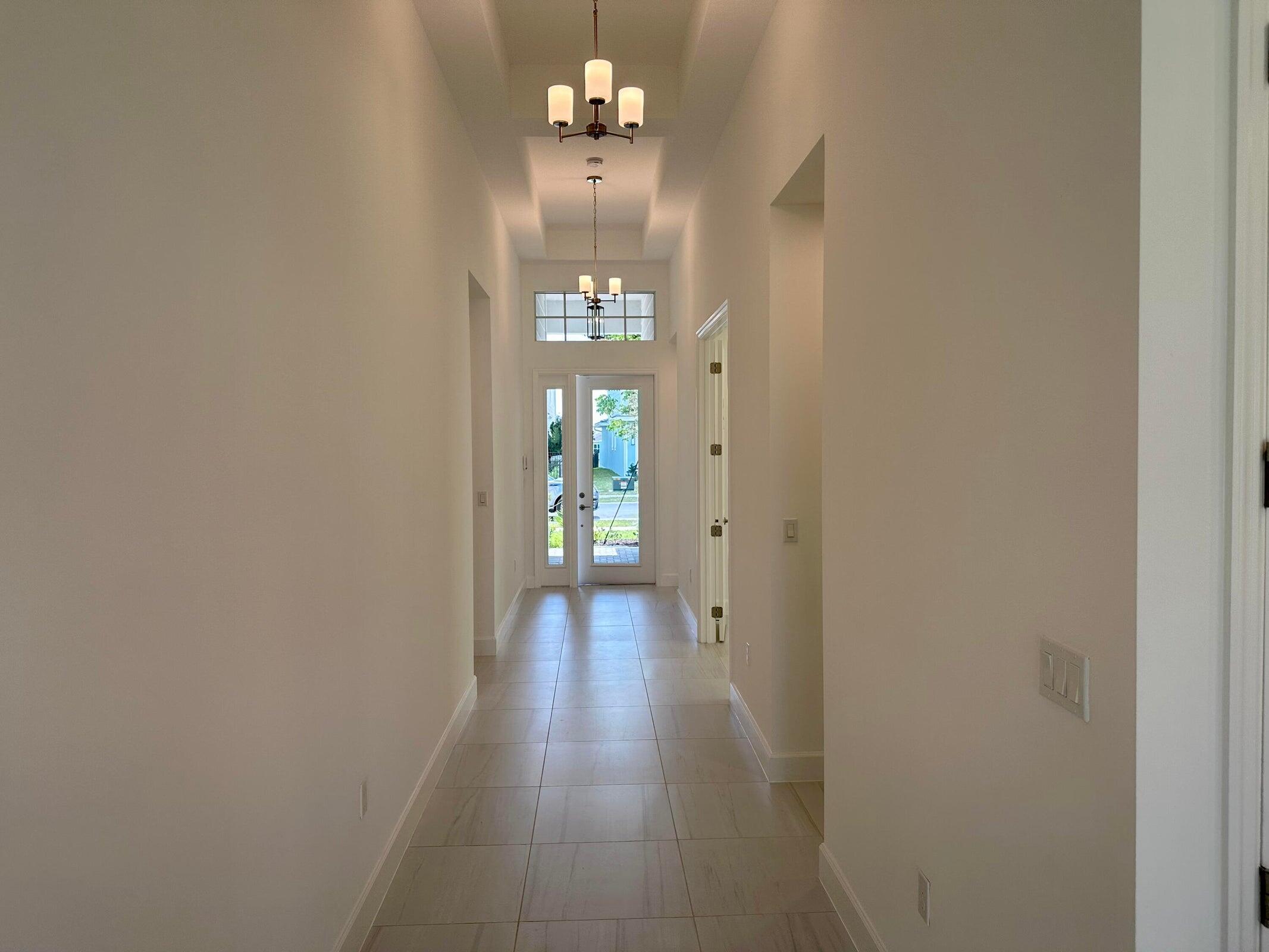 1346 Harvester Crossing Loxahatchee, FL 33470 - Photo 8 of 43 a very nice looking hallway with a chandelier