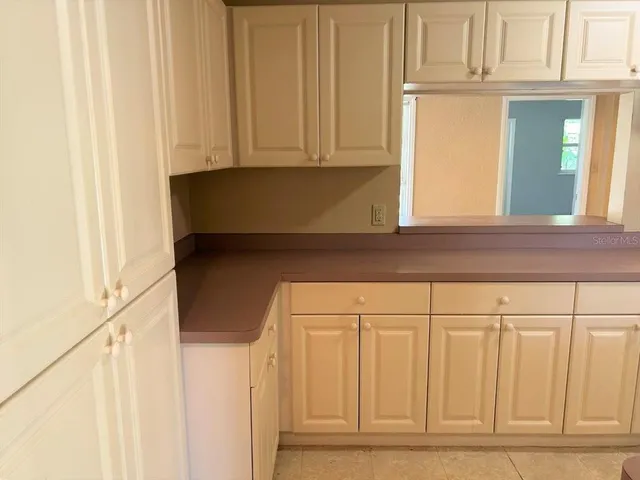 a kitchen with granite countertop white cabinets and a refrigerator