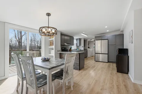 a view of a dining room and livingroom with furniture wooden floor a chandelier