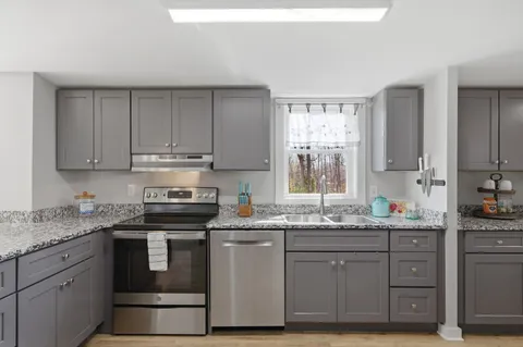 a kitchen with stainless steel appliances granite countertop a sink stove and cabinets