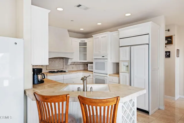 a kitchen with stainless steel appliances granite countertop a sink stove refrigerator and cabinets