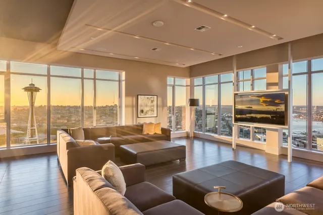 a living room with furniture floor to ceiling window wooden floor and a flat screen tv