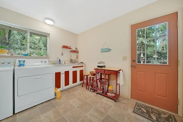 a utility room with stainless steel appliances a stove a sink and a window