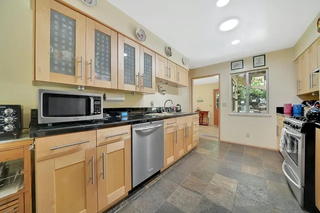 a kitchen with stainless steel appliances granite countertop a stove a sink and white cabinets