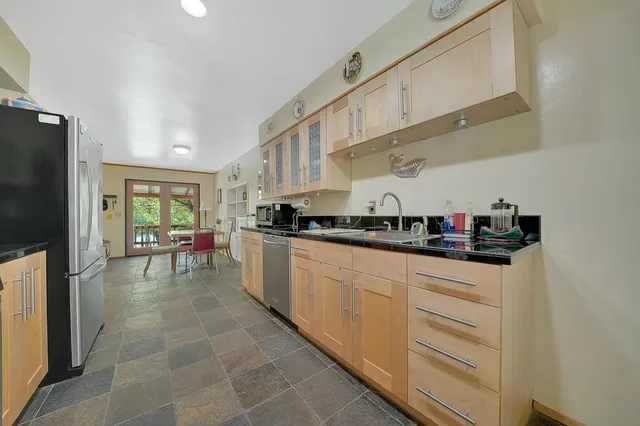 a dining hall with stainless steel appliances granite countertop a couch and a dining table with chairs