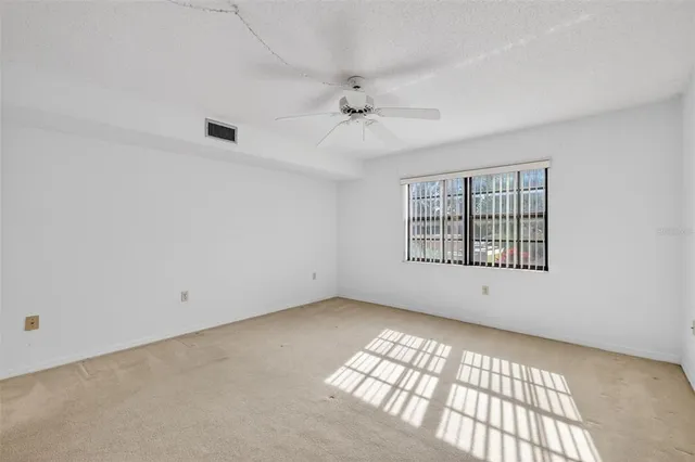 an empty room with windows and ceiling fan view