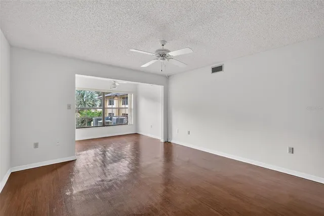 an empty room with windows and ceiling fan