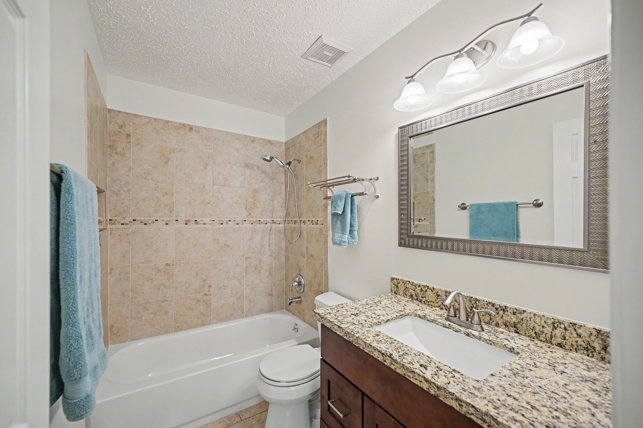 17019 Fordingbridge Court Spring, TX 77379 - Photo 19 of 26 Well-appointed secondary bathroom conveniently located in the hall and designed to serve the additional bedrooms. Features include a granite vanity countertop with ample cabinetry, a large framed mirror, and updated lighting. The tub and shower combination is surrounded by neutral tile with a decorative accent border, while tile flooring provides durability and easy maintenance. A clean, neutral palette makes this bathroom both functional and inviting.