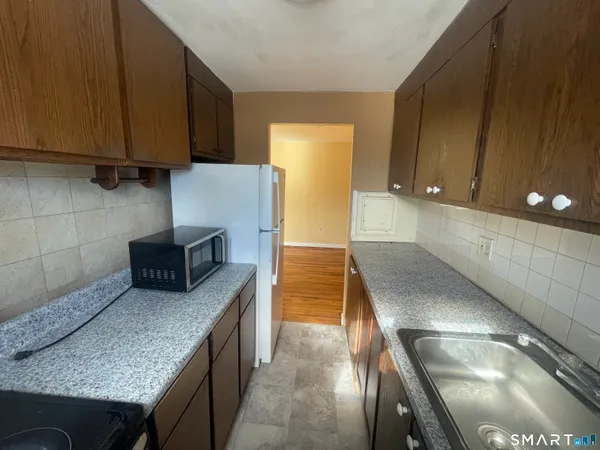 a kitchen with granite countertop a sink a stove and a microwave oven in a cabinets
