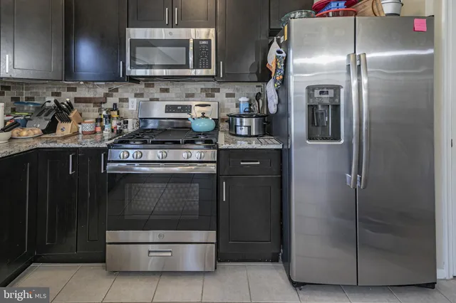 a kitchen with stainless steel appliances granite countertop a stove a refrigerator and a sink