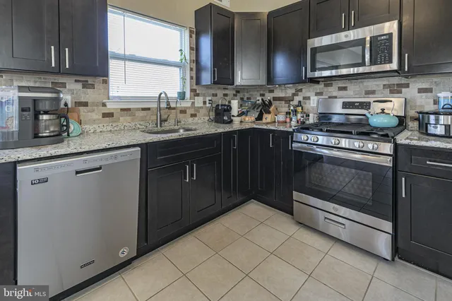 a kitchen with stainless steel appliances granite countertop a sink stove and microwave