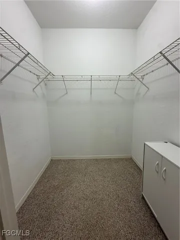 an empty room with chandelier fan and windows