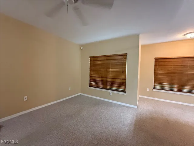 an empty room with a chandelier fan and windows