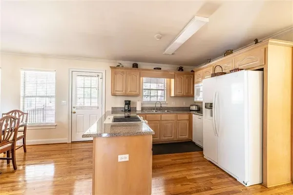 a kitchen with a refrigerator a stove a sink dishwasher with a dining table and chairs with wooden floor