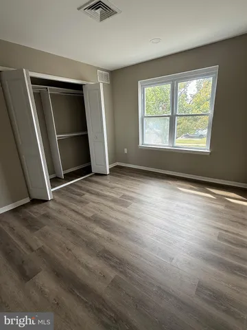 an empty room with wooden floor closet and windows