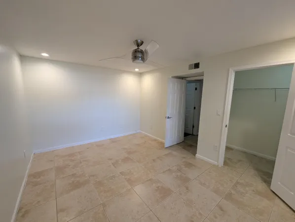 an empty room with chandelier fan and windows