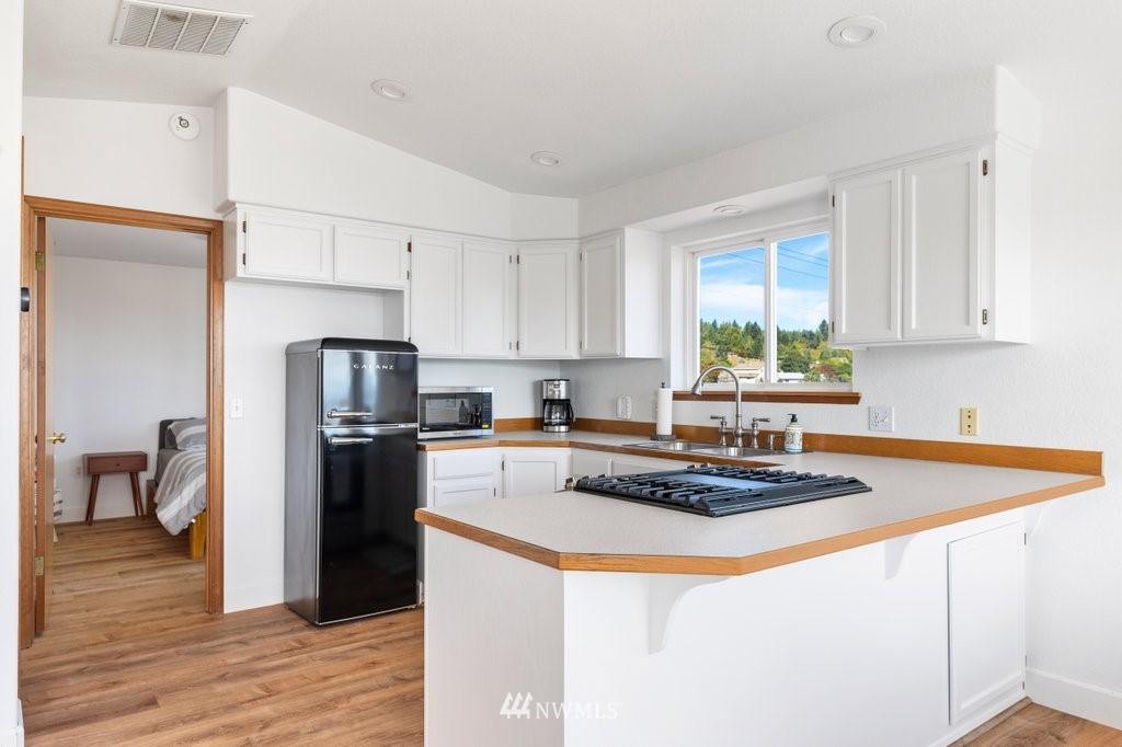 6623 Humphrey Road Clinton, WA 98236 - Photo 18 of 40 a kitchen with stainless steel appliances granite countertop a refrigerator a stove a sink dishwasher and a refrigerator with wooden floor