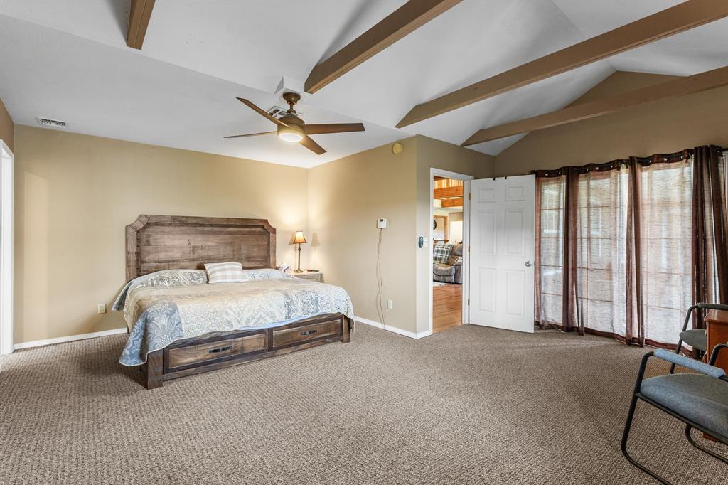 13315 Highway 281 Scotland, TX 76379 - Photo 15 of 40 Primary bedroom with vaulted ceiling featuring exposed beams, ceiling fan, and access to back patio