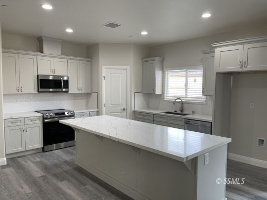 846 Harriet Street Ridgecrest, CA 93555 - Photo 2 of 21 a large kitchen with stainless steel appliances a sink a stove a microwave a refrigerator a center island and cabinets