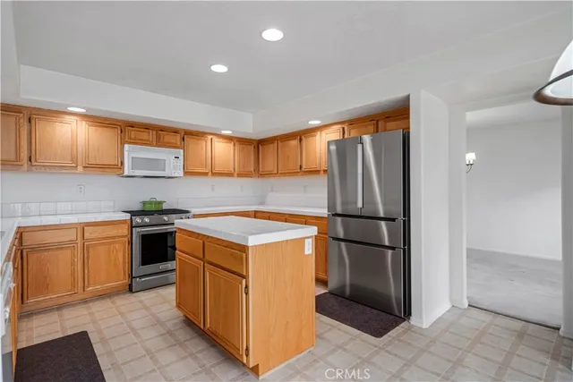 a kitchen with stainless steel appliances granite countertop a refrigerator a stove a sink and a microwave