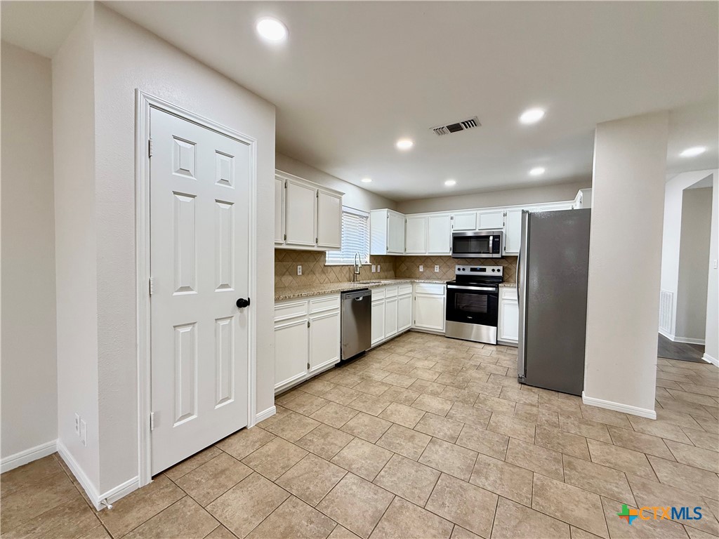 210 Stone Gate Drive Victoria, TX 77904 - Photo 7 of 23 a large kitchen with a refrigerator and white cabinets