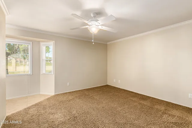 an empty room with a chandelier fan and windows