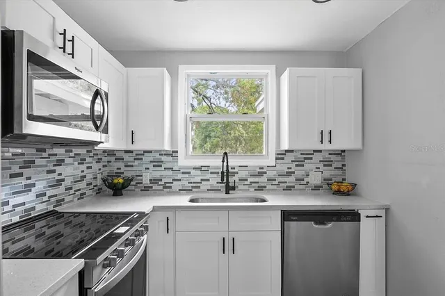 a kitchen with stainless steel appliances granite countertop a sink stove and cabinets